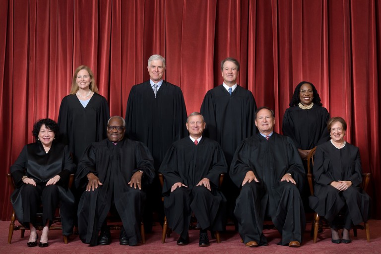Formal group photograph of the Supreme Court as it was been comprised on June 30, 2022 after Justice Ketanji Brown Jackson joined the Court. The Justices are posed in front of red velvet drapes and arranged by seniority, with five seated and four standing. Seated from left are Justices Sonia Sotomayor, Clarence Thomas, Chief Justice John G. Roberts, Jr., and Justices Samuel A. Alito and Elena Kagan. Standing from left are Justices Amy Coney Barrett, Neil M. Gorsuch, Brett M. Kavanaugh, and Ketanji Brown Jackson. Credit: Fred Schilling, Collection of the Supreme Court of the United States.