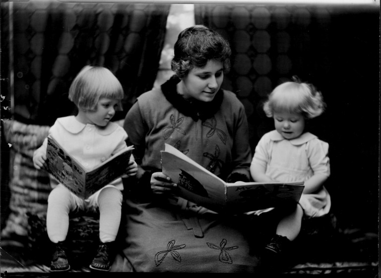 Student reading to two little girls. Photographed for 1920 home economics catalog by Troy. Collection: Human Ecology Historical Photographs.